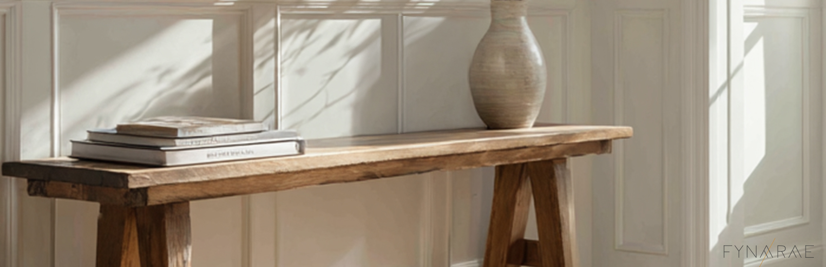Light filtering into a room. A segment of the space that creates calm. A simple bench top with books and a vase.
